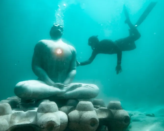 Plongeur touche une statue connectée posée dans un fond marin