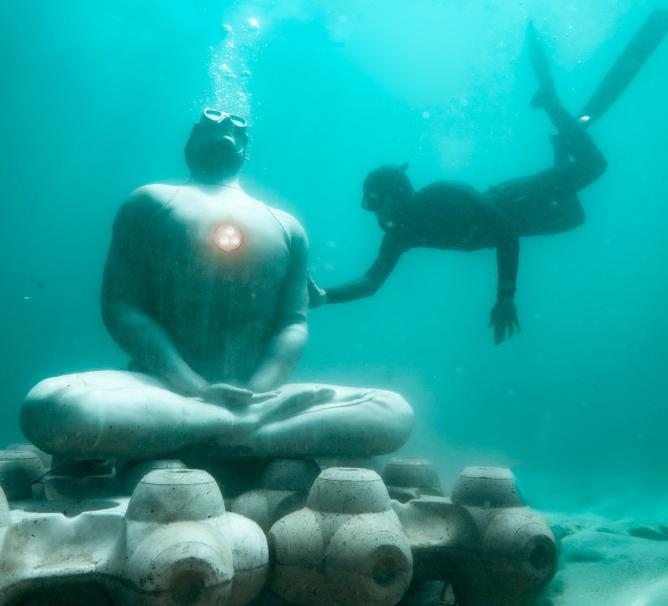Plongeur touche une statue connectée posée dans un fond marin
